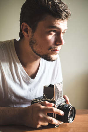 young stylish hipster man with old camera on the table at home