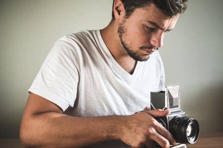 young stylish hipster man with old camera on the table at home