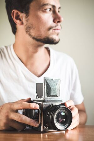 young stylish hipster man with old camera on the table at home