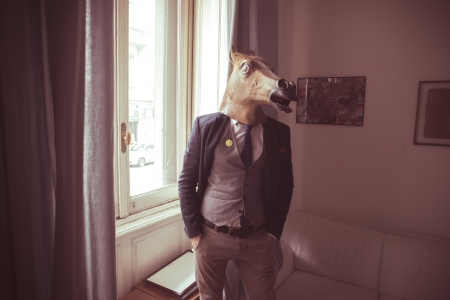 horse mask man in front of window at homeの写真素材
