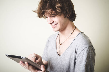 stylish young blonde hipster man using tablet on white backgroundの写真素材