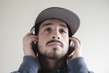 young stylish man listening to music on gray backgroundの写真素材