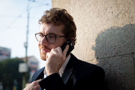 elegant attractive fashion hipster man on the phone in the city