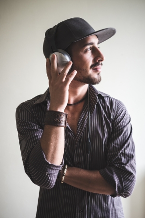 young stylish man listening to music on gray backgroundの写真素材
