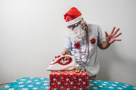 funny santa claus babbo natale ironing on white backgroundの写真素材