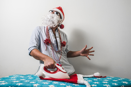 funny santa claus babbo natale ironing on white backgroundの写真素材