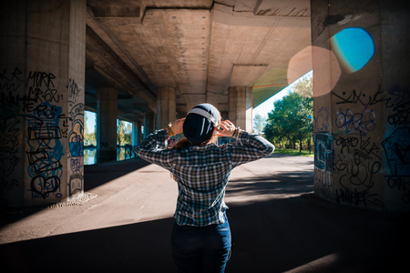 beautiful young blonde hipster woman listening music in urban landscapeの写真素材