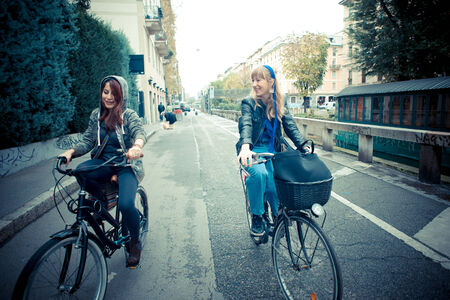 two friends woman on bike in urban contestの写真素材