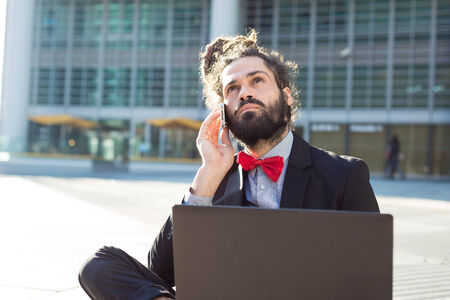 Stylish elegant dreadlocks businessman using notebook in business landscapeの写真素材