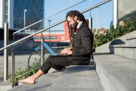 Stylish elegant dreadlocks businessman using notebook in business landscapeの写真素材
