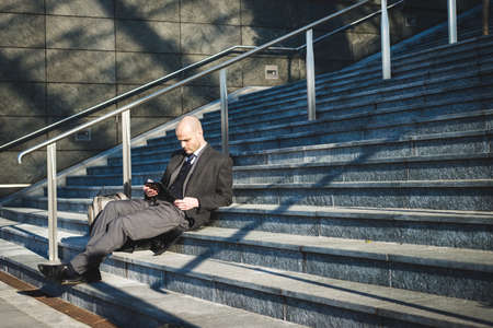 successful elegant fashionable businessman using tablet  in business district