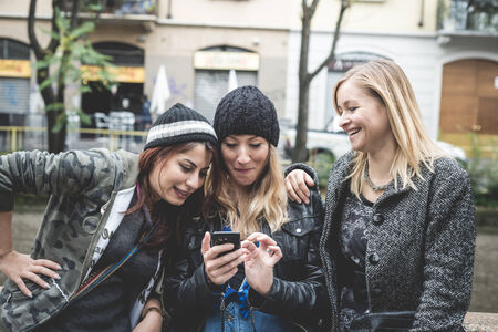 three friends woman on the phone in the streetの写真素材
