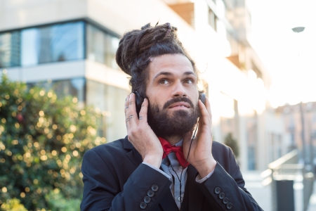 Stylish elegant dreadlocks businessman listening to music in business landscape