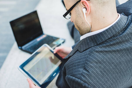 successful elegant fashionable businessman using tablet  in business district