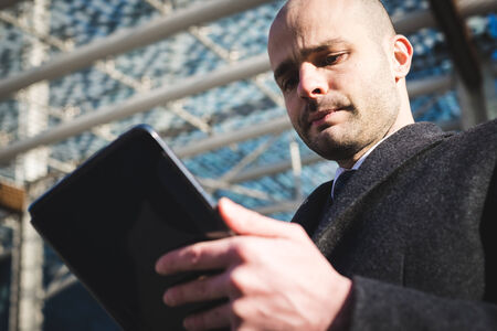 successful elegant fashionable businessman using tablet  in business district