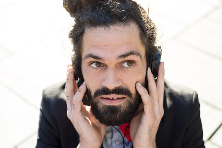 Stylish elegant dreadlocks businessman listening to music in business landscapeの写真素材