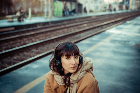 beautiful young woman listening to music headphones  in the city winterの写真素材