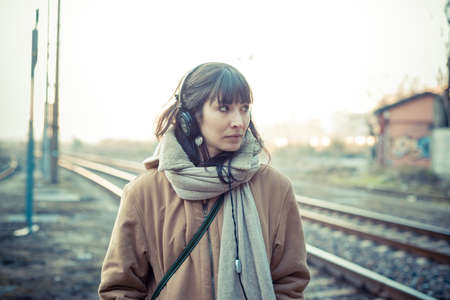 beautiful young woman listening to music headphones  in the city winterの写真素材