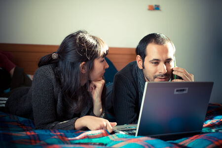 couple in love on the bed using notebook at homeの写真素材
