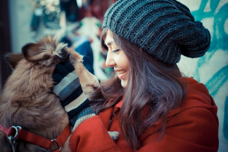 beautiful woman with red coat in winter hugging the dogの写真素材