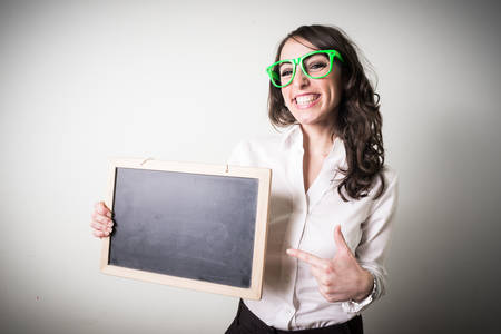 beautiful young businesswoman holding blackboard on gray backgroundの写真素材