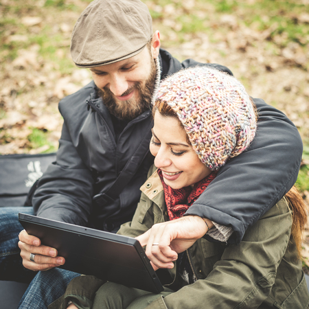 couple in love using tablet connecting web wireless wifi at the park winterの写真素材