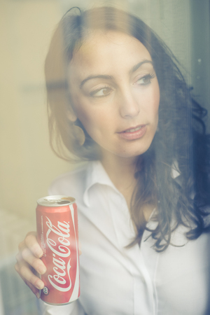 MILAN, ITALY - JANUARY 16, 2014: Beautiful woman drinking coca cola bottle can 33 cl. Coca Cola is the most famous brand soft drink in the worldのeditorial素材