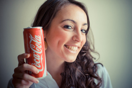 MILAN, ITALY - JANUARY 16, 2014: Beautiful woman drinking coca cola bottle can 33 cl. Coca Cola is...