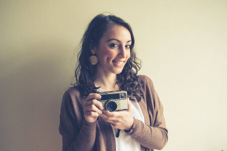 beautiful woman holding old camera at home の写真素材