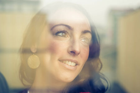 beautiful woman at home facing through windowの写真素材