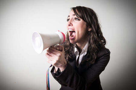 beautiful young businesswoman with little megaphone on gray backgroundの写真素材