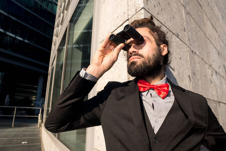 Stylish elegant dreadlocks businessman binoculars in business landscapeの写真素材
