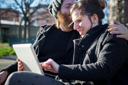 young couple in love lifestyle outdoor using tablet at the parkの写真素材