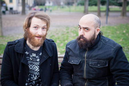 two bearded modern man working on tablet at the park