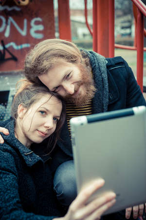 young modern stylish couple using tablet outdoors