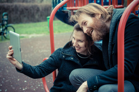 young modern stylish couple using tablet outdoors