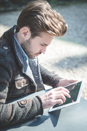 young handsome fashion model using tablet man outdoorsの写真素材