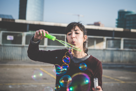 young beautiful hipster woman bubble blower in the city