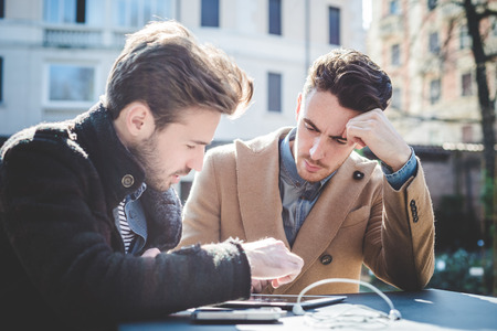 two young handsome fashion model businessmen using tablet  outdoorsの写真素材