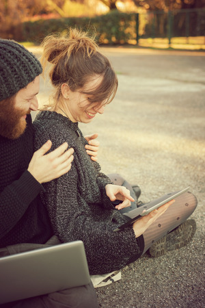 young couple in love lifestyle outdoor using tablet at the parkの写真素材