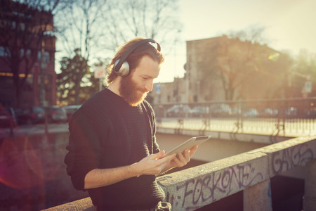 young stylish bearded man listening to music in the cityの写真素材