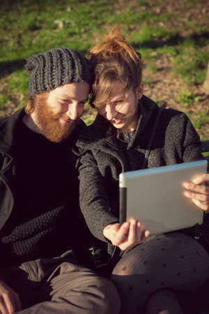 young couple in love lifestyle outdoor using tablet at the parkの写真素材