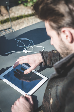 young handsome fashion model using tablet man outdoorsの写真素材