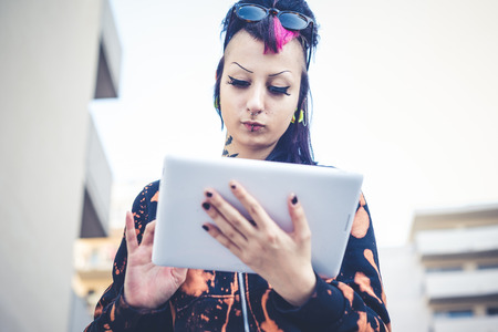 young beautiful punk dark girl using tablet in urban landscapeの写真素材