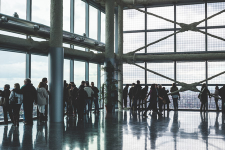 people silouette looking through windows of high view skyscraper