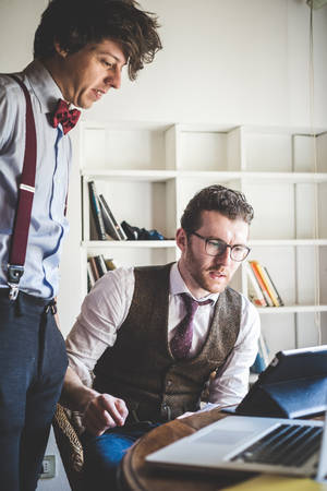 two young hipster stylish elegant men working with notebook and tablet at home の写真素材