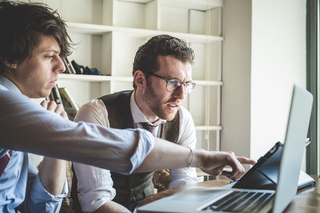 two young hipster stylish elegant men working with notebook and tablet at home 