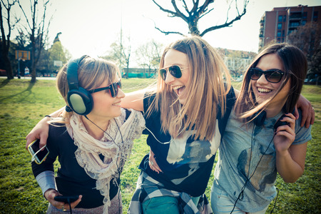 three beautiful friends authentic in urban contest listening to musicの写真素材