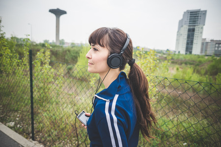 beautiful woman walking and listening music in a desolate lurban landscapeの写真素材