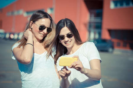 two beautiful young women using smart phone in the cityの写真素材